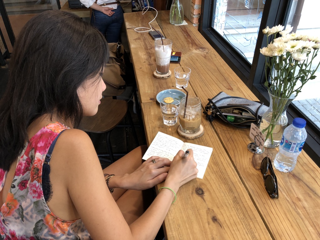 A photo of Melanie Tito writing in a cafe in Chiang Mai, Thailand