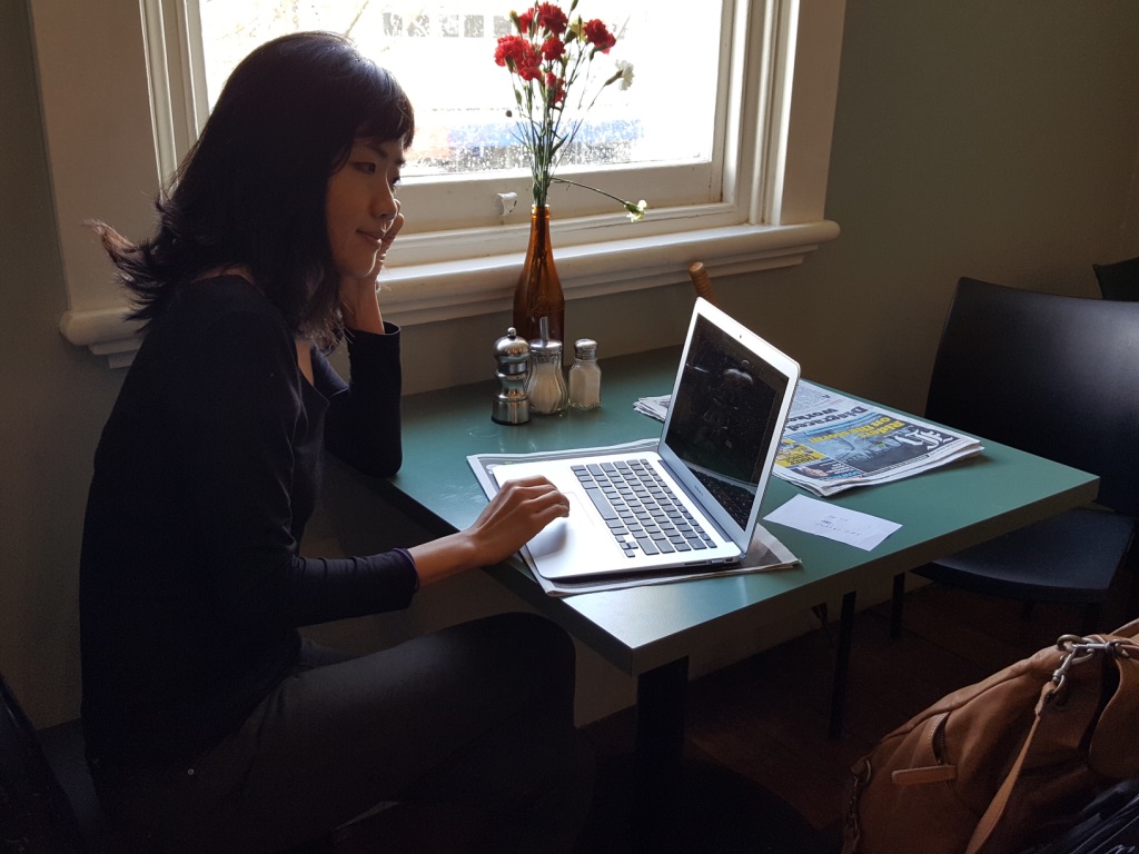 A photo of Melanie Tito writing in a cafe